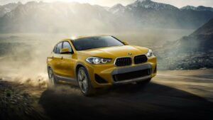 Novo BMW X2, na cor amarela andando na terra
